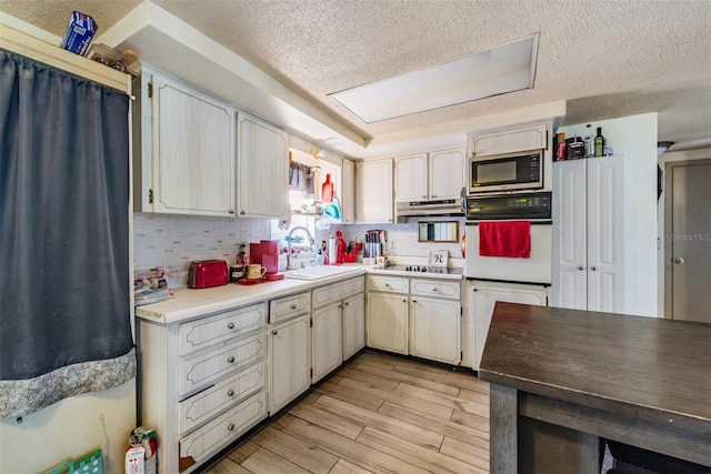 kitchen with decorative backsplash, black electric cooktop, a textured ceiling, built in microwave, and a sink