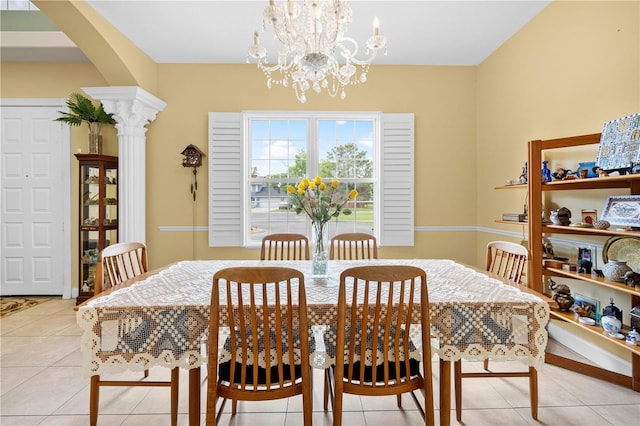 dining space with light tile patterned flooring, a chandelier, arched walkways, and decorative columns