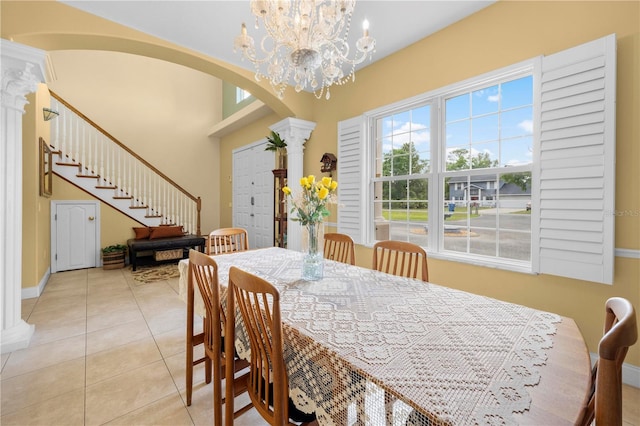 dining space featuring ornate columns, arched walkways, light tile patterned floors, baseboards, and stairs