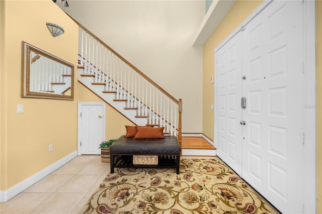foyer entrance featuring stairway, baseboards, and light tile patterned flooring