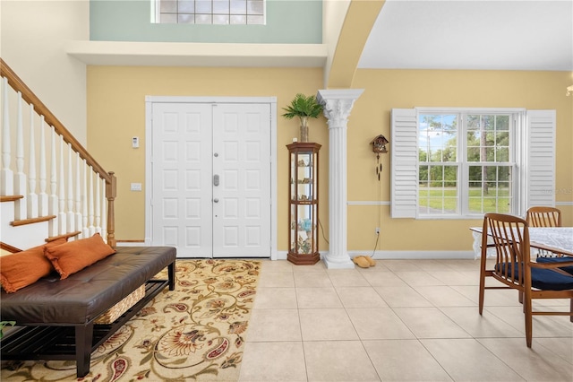 foyer entrance featuring stairway, decorative columns, light tile patterned flooring, and baseboards