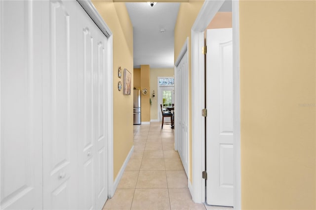 corridor with light tile patterned floors and baseboards