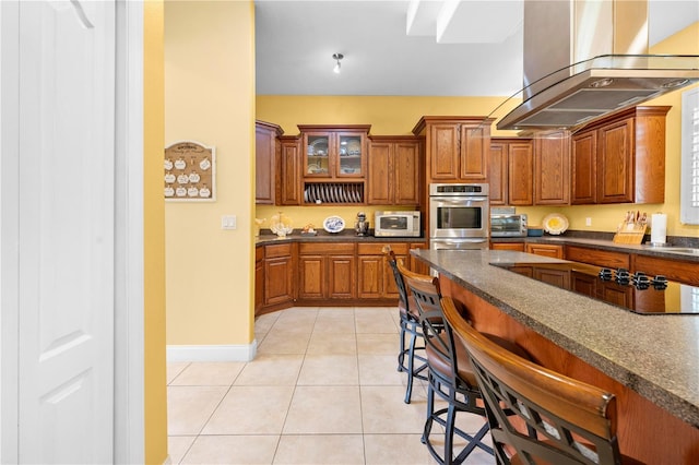 kitchen with white microwave, oven, dark countertops, brown cabinets, and a kitchen bar