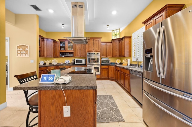 kitchen featuring appliances with stainless steel finishes, island range hood, a kitchen breakfast bar, a sink, and light tile patterned floors