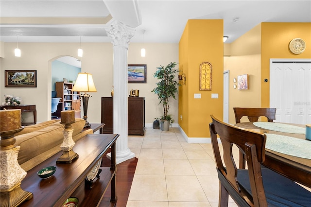 dining space featuring decorative columns, arched walkways, baseboards, and light tile patterned floors