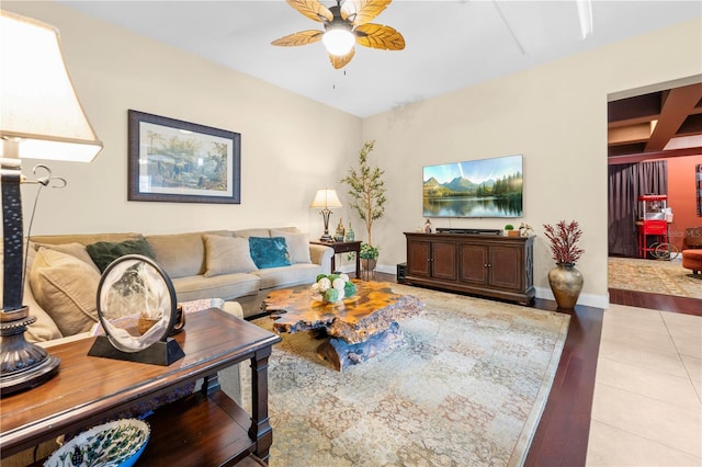 living room featuring ceiling fan, beamed ceiling, baseboards, light tile patterned floors, and coffered ceiling