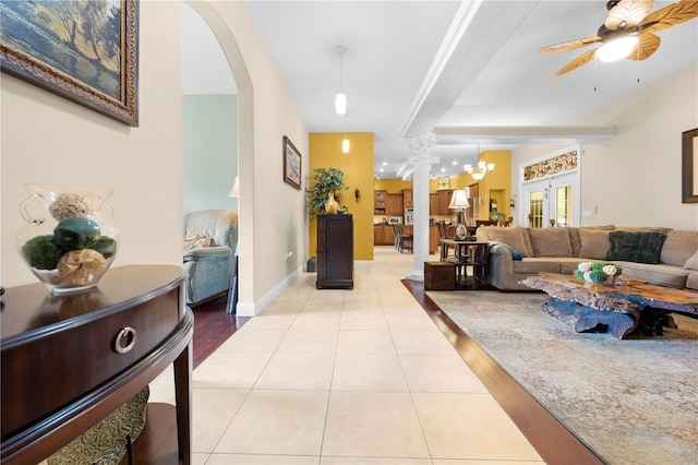 living area with light tile patterned floors, a ceiling fan, arched walkways, and baseboards