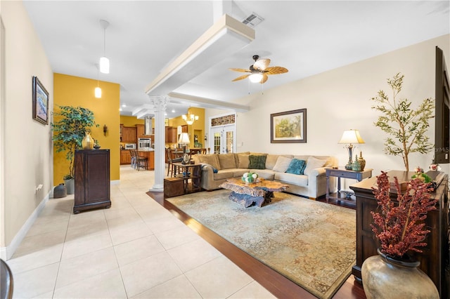 living room featuring light tile patterned flooring, a ceiling fan, decorative columns, and baseboards