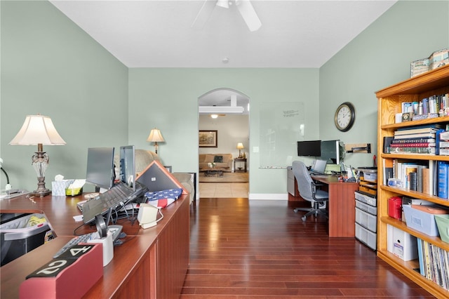 home office featuring ceiling fan, wood finished floors, arched walkways, and baseboards