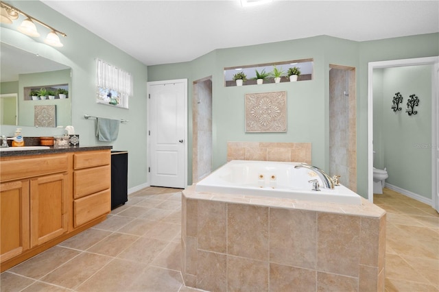 full bathroom with tile patterned floors, toilet, a whirlpool tub, and vanity