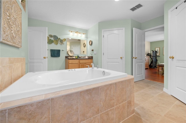 full bathroom with a garden tub, vanity, and tile patterned flooring
