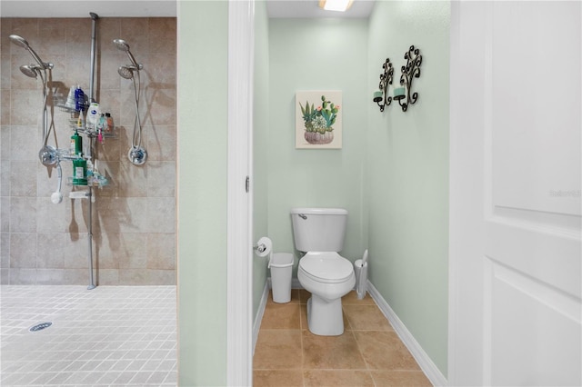 full bath with tiled shower, toilet, tile patterned flooring, and baseboards
