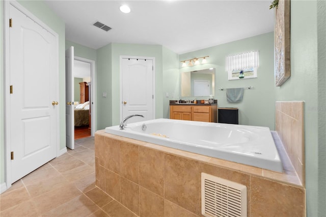 ensuite bathroom featuring a garden tub, tile patterned flooring, and vanity