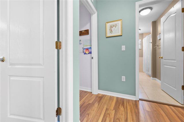hall with light wood-style flooring and baseboards