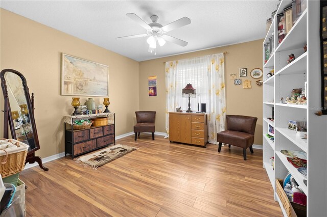 living area featuring light wood finished floors, ceiling fan, and baseboards
