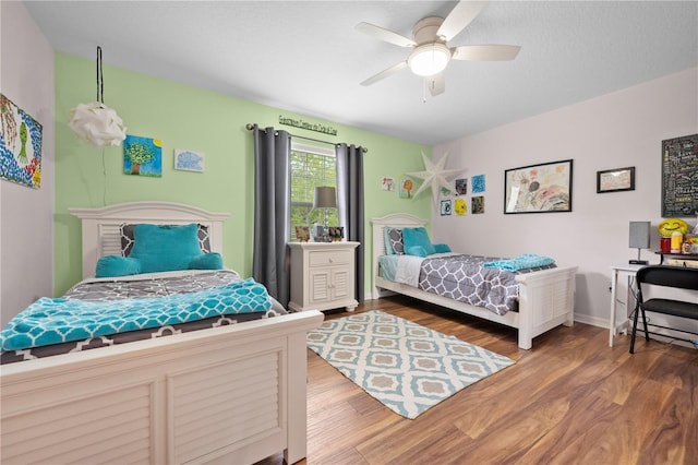 bedroom featuring wood finished floors, a ceiling fan, and baseboards