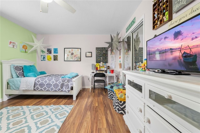 bedroom with wood finished floors, a ceiling fan, and baseboards