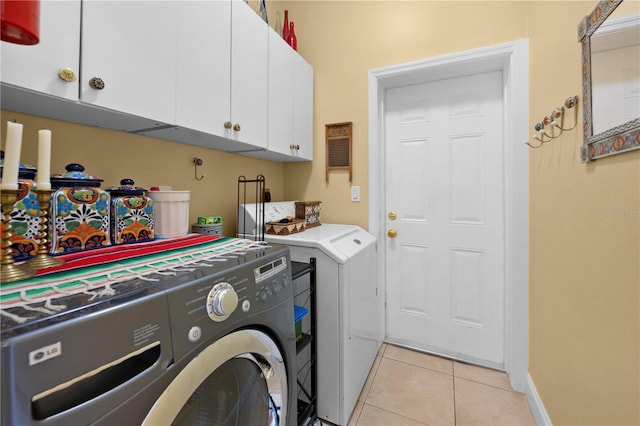 laundry area with separate washer and dryer, cabinet space, and light tile patterned floors
