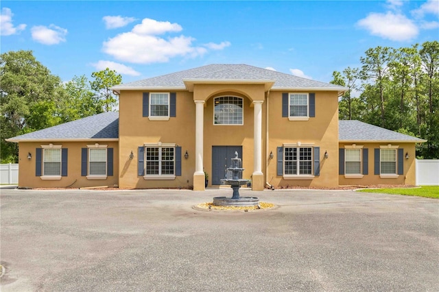 view of front of house featuring stucco siding, fence, and a shingled roof