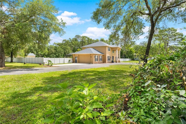 rear view of house with driveway, a garage, and stucco siding