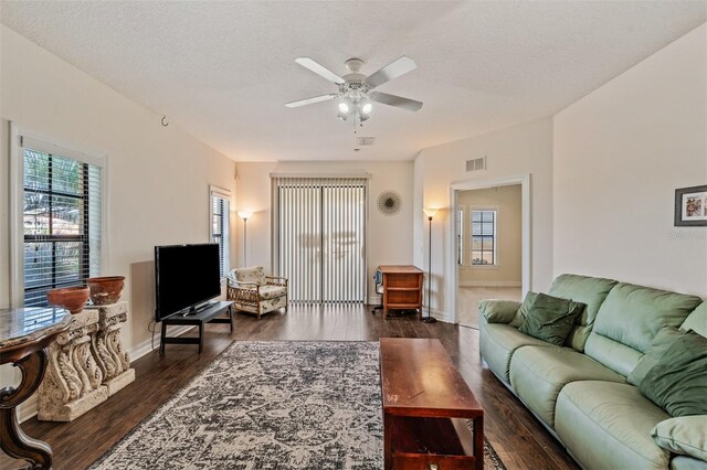 living room with ceiling fan, healthy amount of natural light, dark wood finished floors, and baseboards
