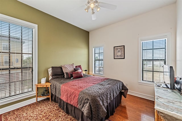 bedroom featuring baseboards, wood finished floors, and ceiling fan