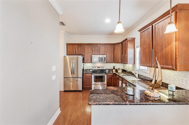 kitchen featuring appliances with stainless steel finishes, dark stone countertops, backsplash, crown molding, and a sink