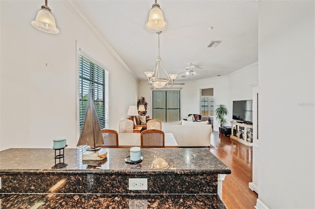 dining space with crown molding, light wood-style flooring, and ceiling fan