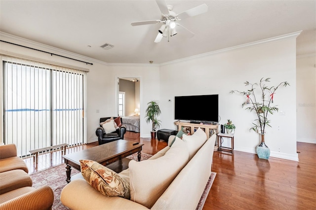 living room featuring ornamental molding, wood finished floors, baseboards, and ceiling fan