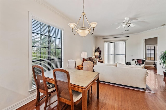 dining space featuring crown molding, a chandelier, hardwood / wood-style flooring, ceiling fan, and baseboards