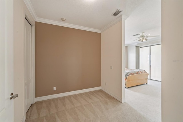 unfurnished bedroom with light carpet, crown molding, baseboards, and a ceiling fan
