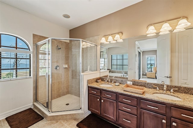 bathroom with a shower stall, double vanity, tile patterned flooring, and baseboards