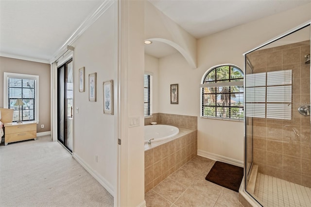 full bath featuring plenty of natural light, a stall shower, a garden tub, and baseboards