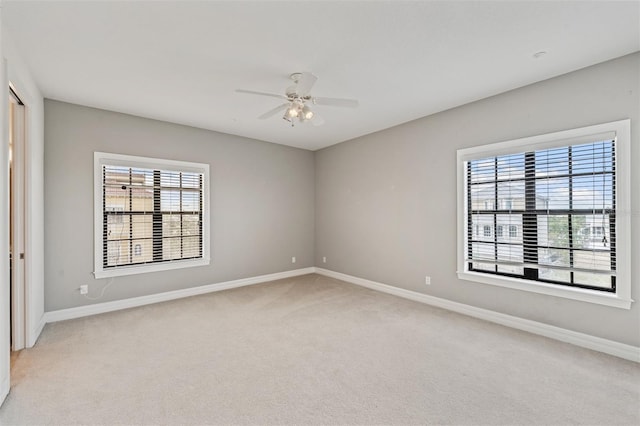 unfurnished room featuring light colored carpet, baseboards, and a ceiling fan