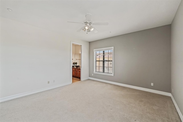 unfurnished room featuring light colored carpet, baseboards, and a ceiling fan