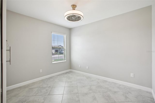 empty room with baseboards and light tile patterned floors