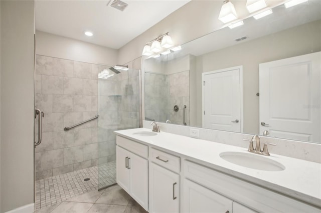 full bathroom with double vanity, visible vents, a tile shower, and a sink