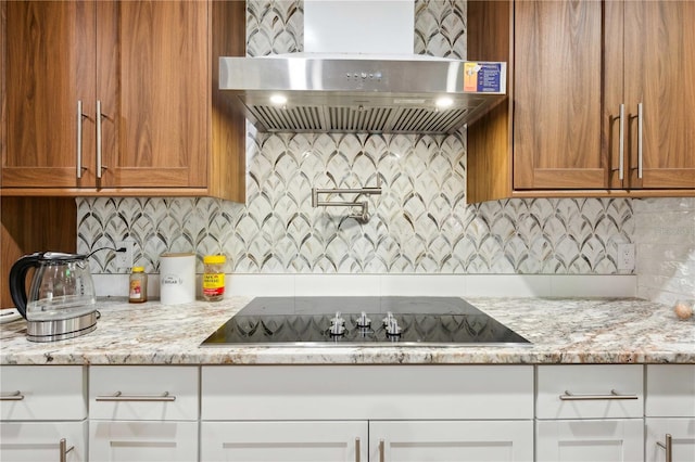 36601 Roberts Rd, Dade City, FL 33525 - kitchen with decorative backsplash, light stone countertops, black electric cooktop, brown cabinets, and exhaust hood