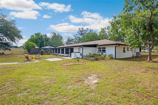 36601 Roberts Rd, Dade City, FL 33525 - rear view of house with fence, stucco siding, a sunroom, central air condition unit, and a yard