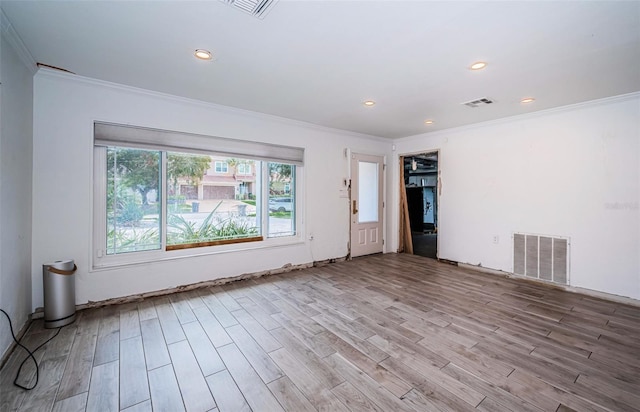 empty room featuring visible vents, ornamental molding, and wood finished floors