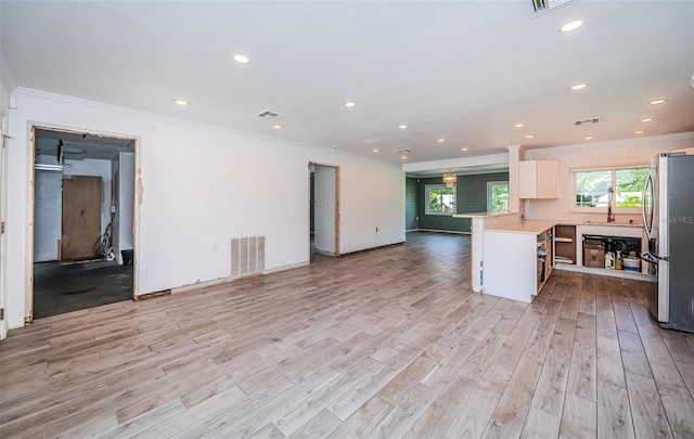 kitchen featuring visible vents, crown molding, freestanding refrigerator, open floor plan, and light wood-style floors
