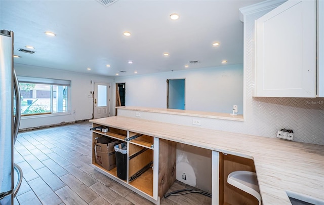 kitchen featuring visible vents, tasteful backsplash, white cabinets, freestanding refrigerator, and recessed lighting