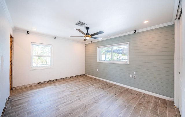 spare room with visible vents, ornamental molding, baseboards, a ceiling fan, and light wood finished floors