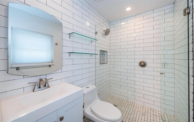 bathroom featuring tile walls, a tile shower, vanity, toilet, and recessed lighting