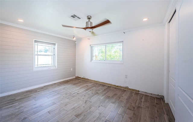 unfurnished room with a healthy amount of sunlight, a ceiling fan, wood finished floors, and visible vents