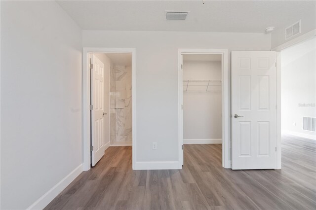 unfurnished bedroom with visible vents, baseboards, and wood finished floors