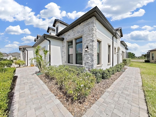 4300 Barletta Ct, Wesley Chapel, FL 33543 - view of home's exterior with stucco siding, stone siding, and a lawn
