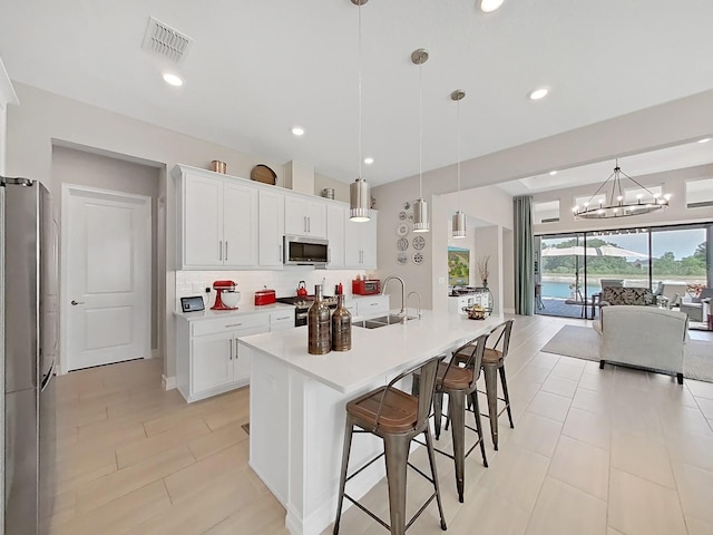4300 Barletta Ct, Wesley Chapel, FL 33543 - kitchen featuring appliances with stainless steel finishes, a sink, a chandelier, open floor plan, and a kitchen bar