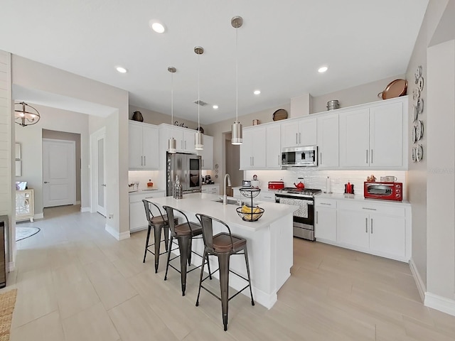 4300 Barletta Ct, Wesley Chapel, FL 33543 - kitchen with stainless steel appliances, a breakfast bar area, decorative backsplash, a kitchen island with sink, and light countertops