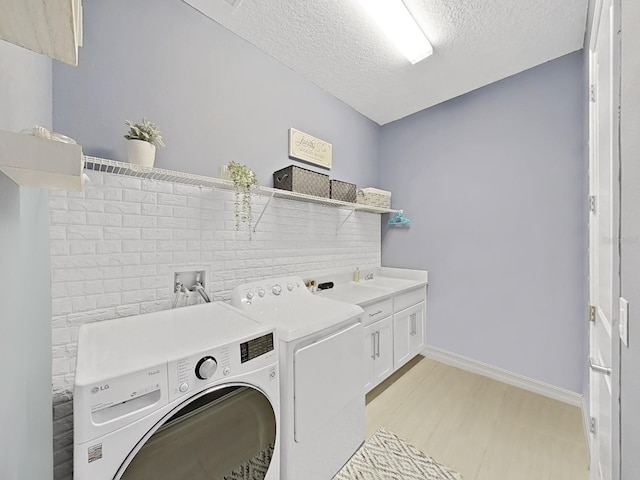 4300 Barletta Ct, Wesley Chapel, FL 33543 - laundry room with washer and dryer, cabinet space, a textured ceiling, baseboards, and light wood-style floors